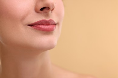 Woman with beautiful lips on beige background, closeup. Space for text