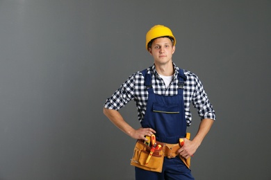 Photo of Electrician with tools wearing uniform on gray background. Space for text