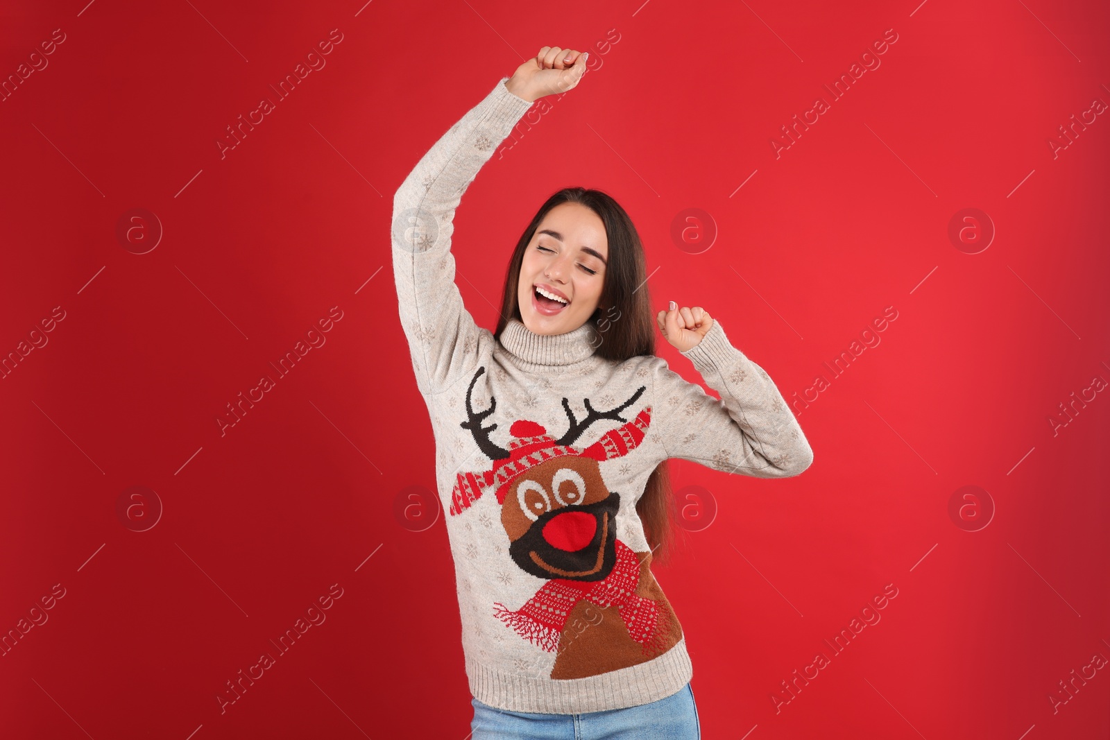 Photo of Young woman in Christmas sweater on red background