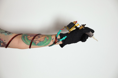 Tattoo artist with professional machine on white background, closeup