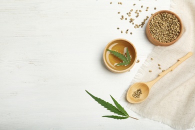 Photo of Hemp oil, seeds and space for text on white wooden background, flat lay