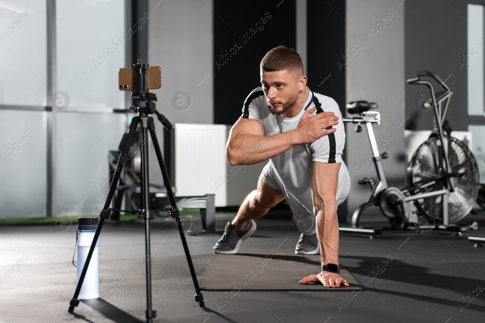 Photo of Trainer streaming online workout with phone at gym