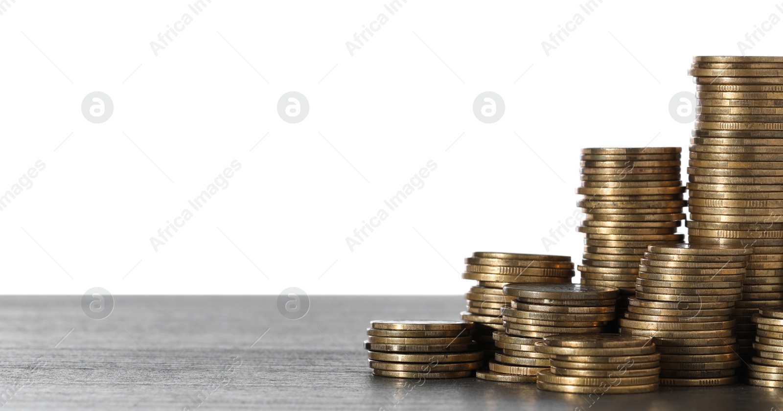 Photo of Stack of coins on wooden table, closeup. Space for text