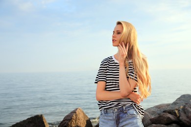 Photo of Beautiful young woman near sea on sunny day, space for text