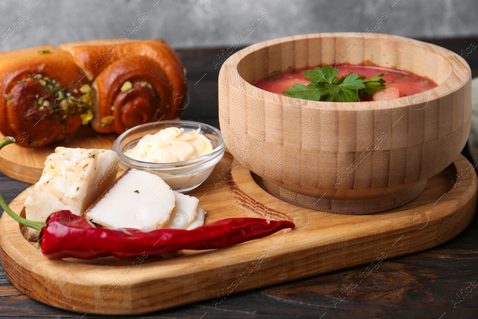 Photo of Delicious borsch served with pampushky and salo on wooden table. Traditional Ukrainian cuisine