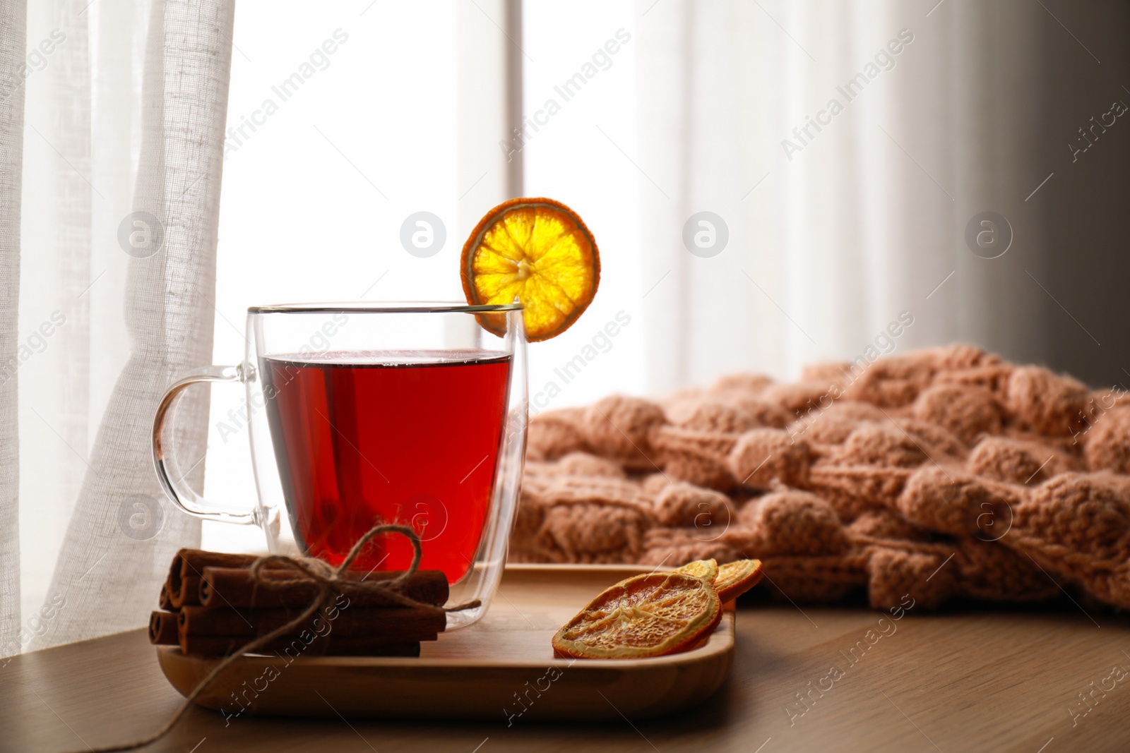 Photo of Cup of hot winter drink and knitted sweater on wooden sill near window. Space for text