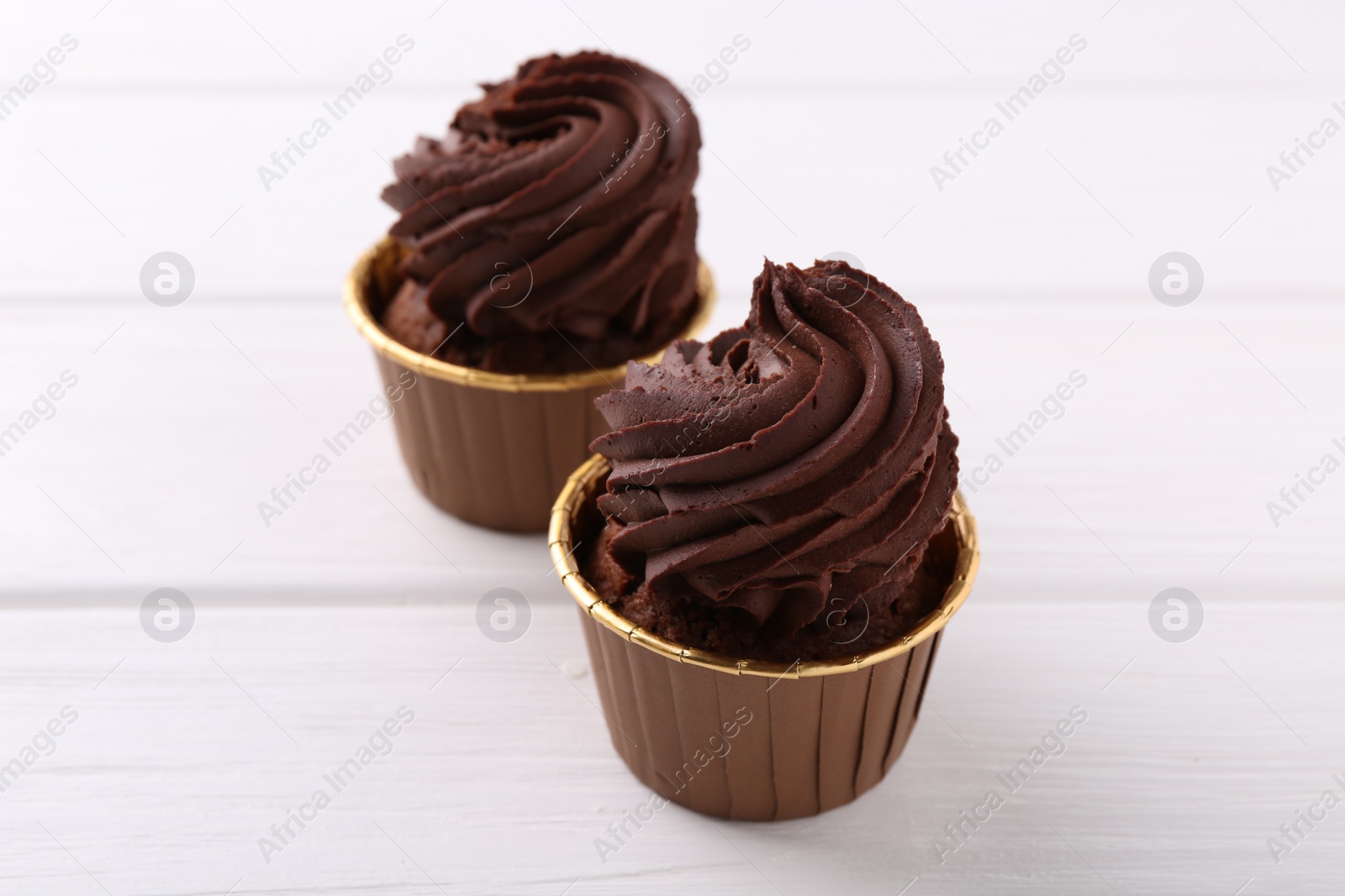 Photo of Delicious chocolate cupcakes on white wooden table