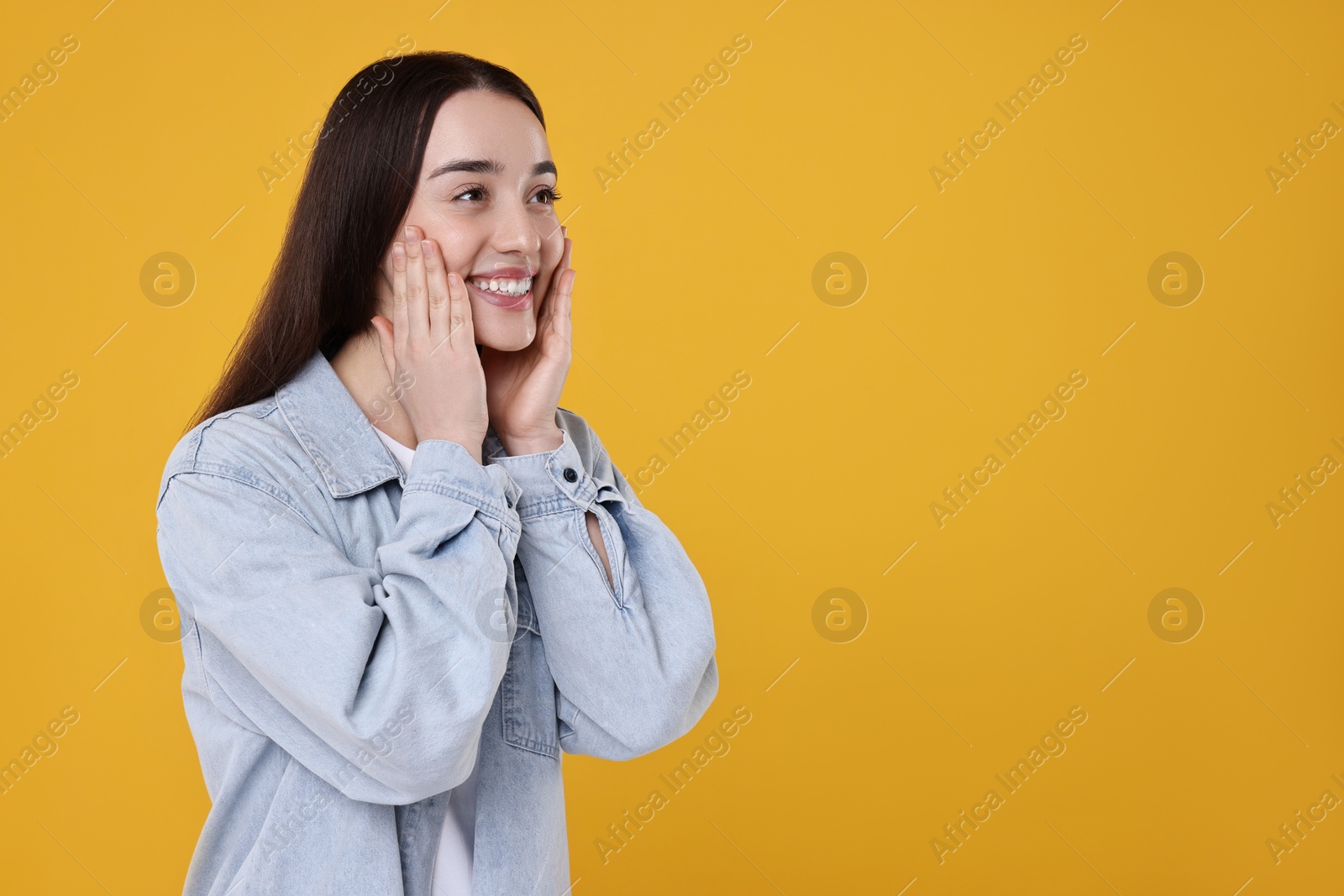 Photo of Portrait of happy surprised woman on yellow background. Space for text