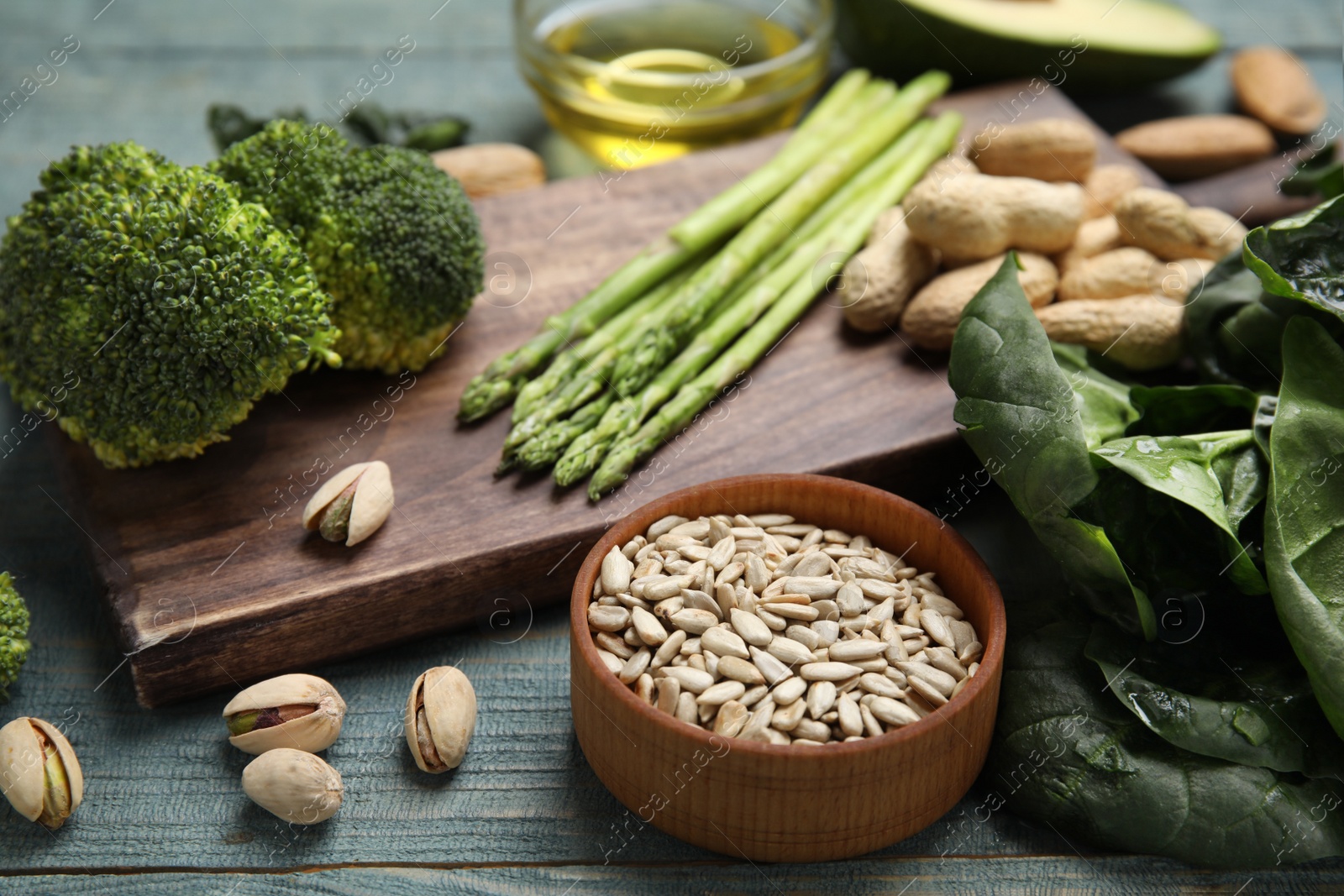 Photo of Different products rich in vitamin E on blue wooden table, closeup