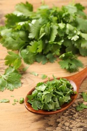 Photo of Fresh green cilantro and spoon on wooden table