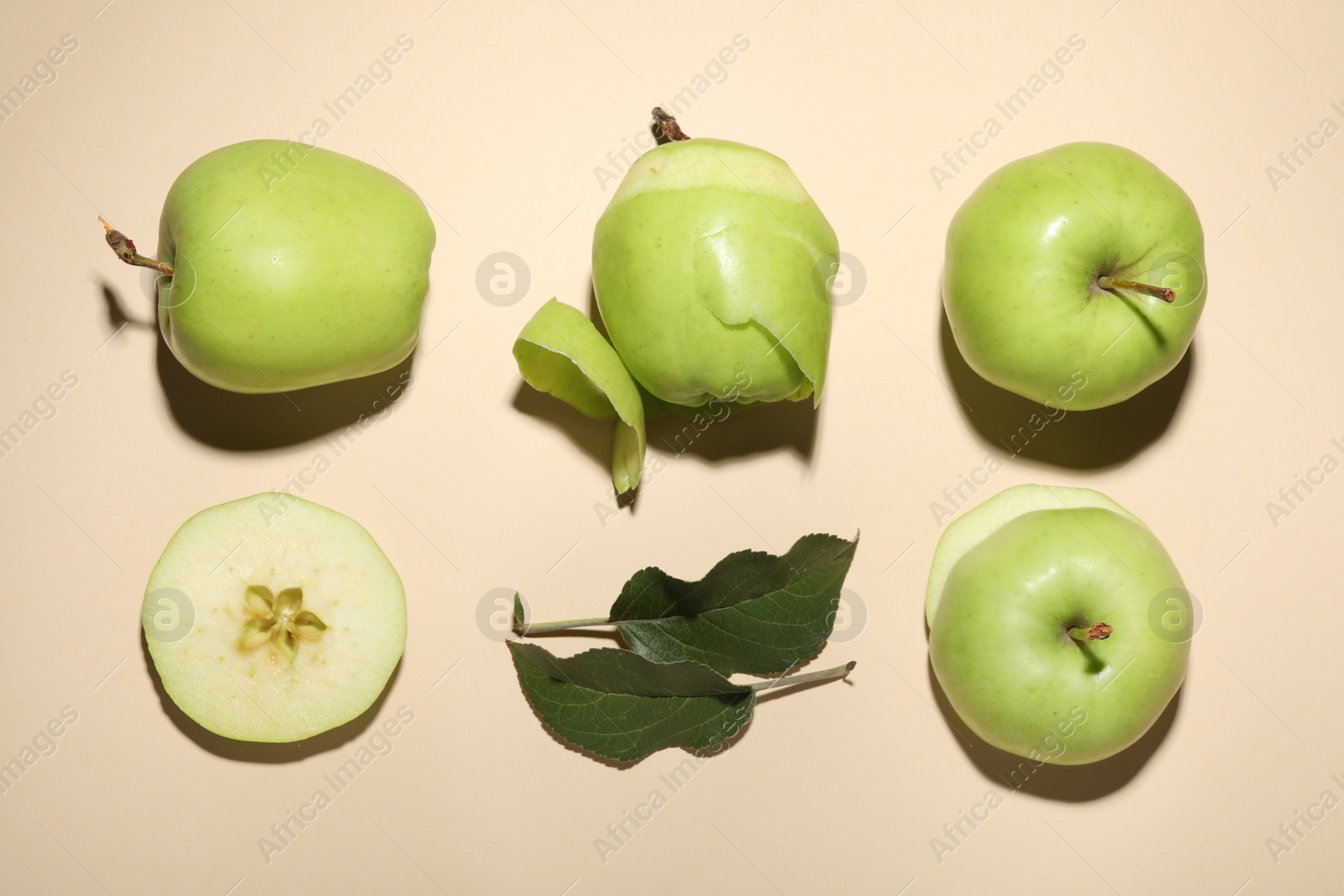 Photo of Whole, cut green apples and leaf on beige background, flat lay