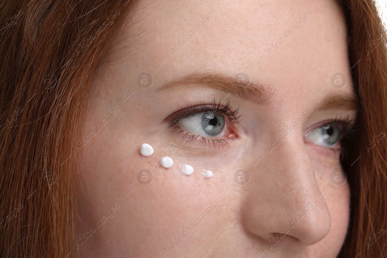 Photo of Beautiful woman with freckles and cream on her face, closeup