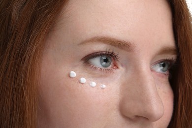 Photo of Beautiful woman with freckles and cream on her face, closeup