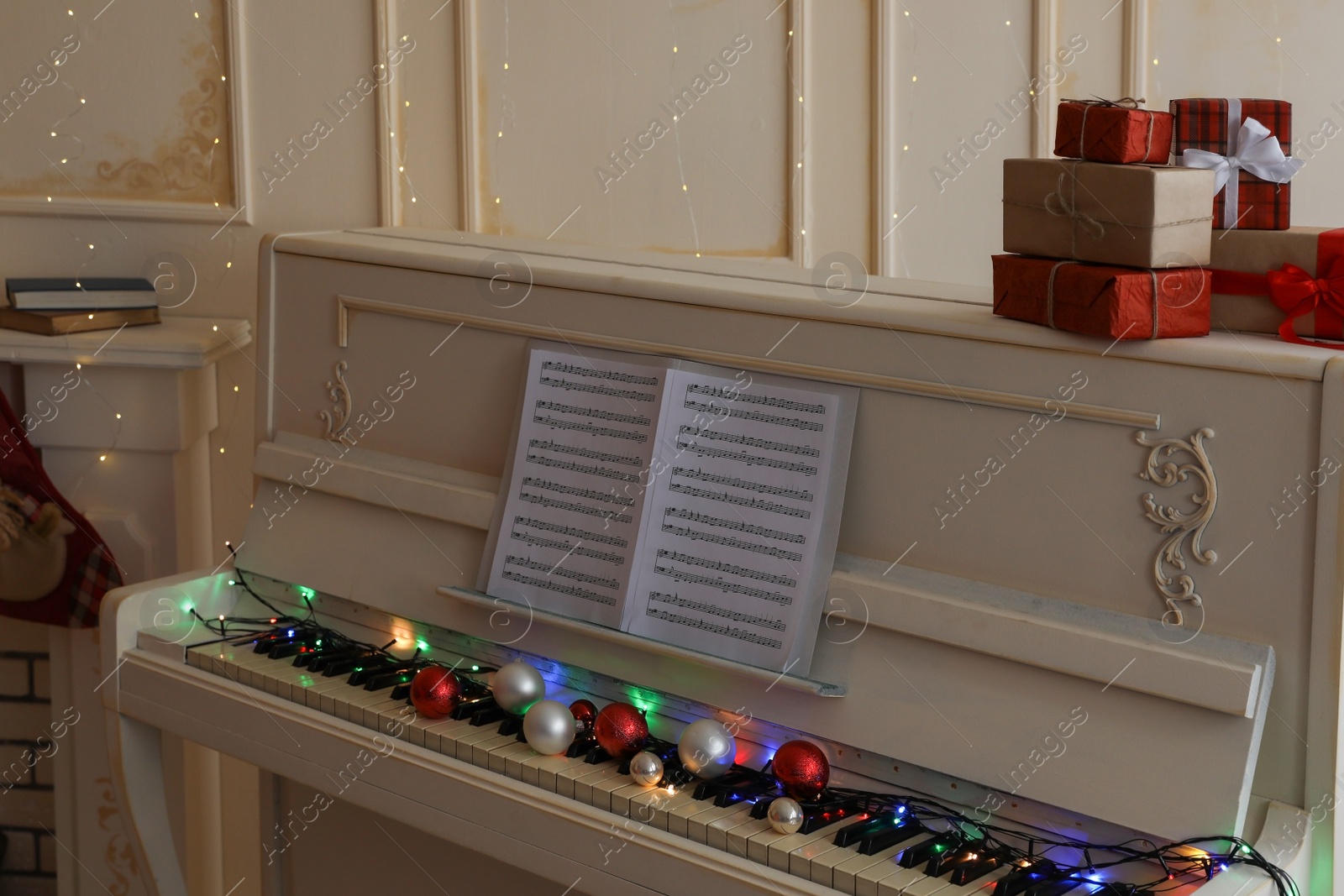 Photo of White piano with festive decor and note sheets indoors. Christmas music