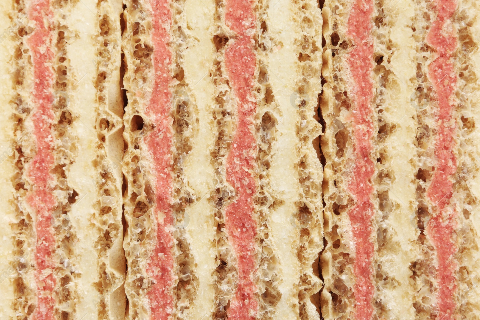 Photo of Wafer sticks with pink filling as background, closeup. Sweet food