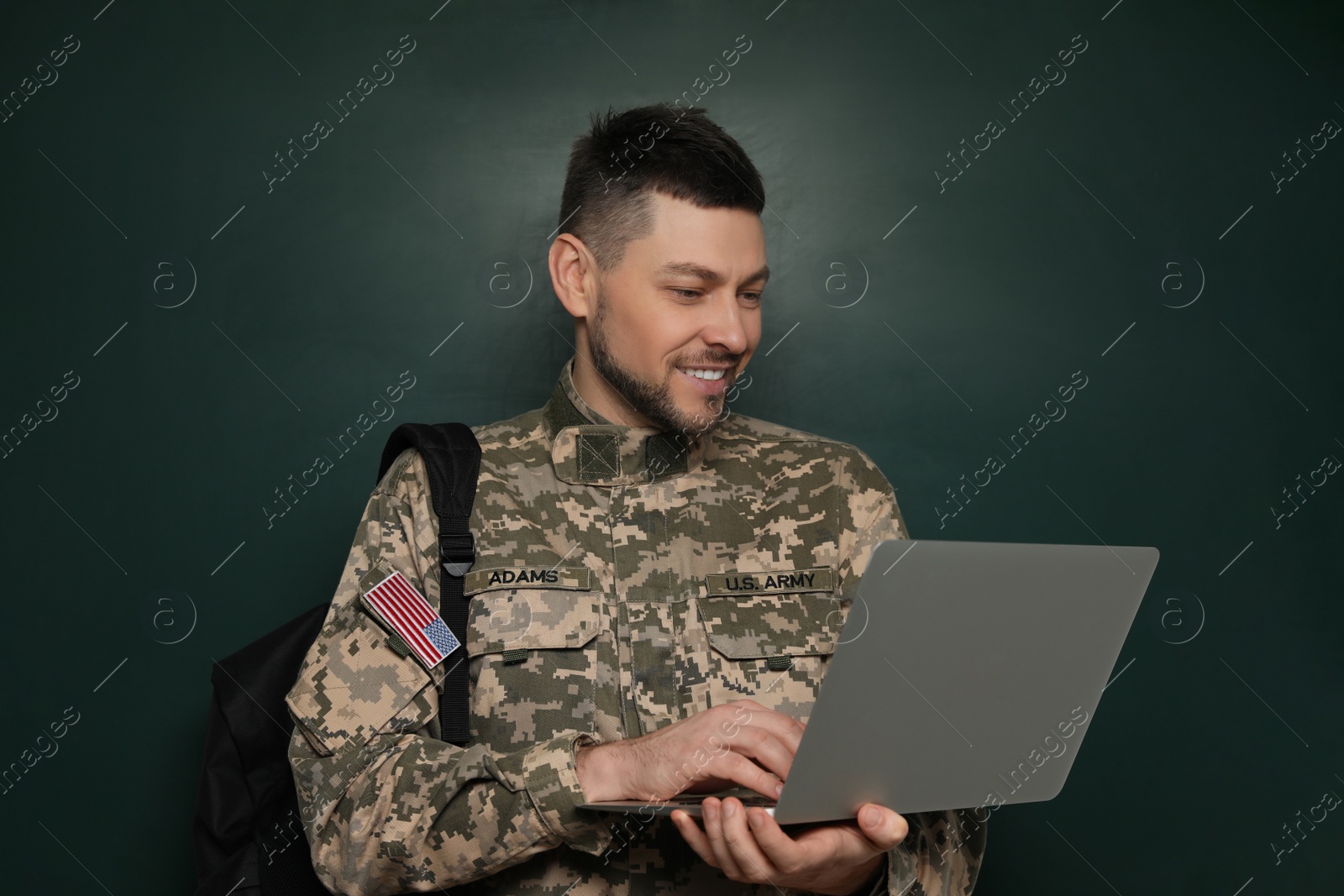 Photo of Cadet with backpack and laptop near chalkboard. Military education