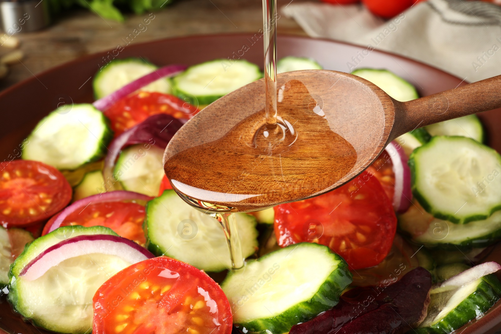 Photo of Adding cooking oil to delicious salad, closeup