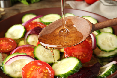 Adding cooking oil to delicious salad, closeup