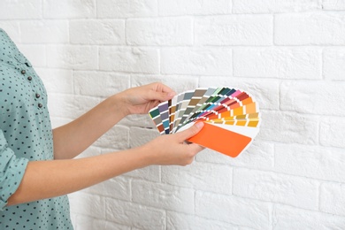 Photo of Female interior designer with color palette samples near brick wall, closeup