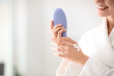 Photo of Young woman applying hand cream at home, closeup