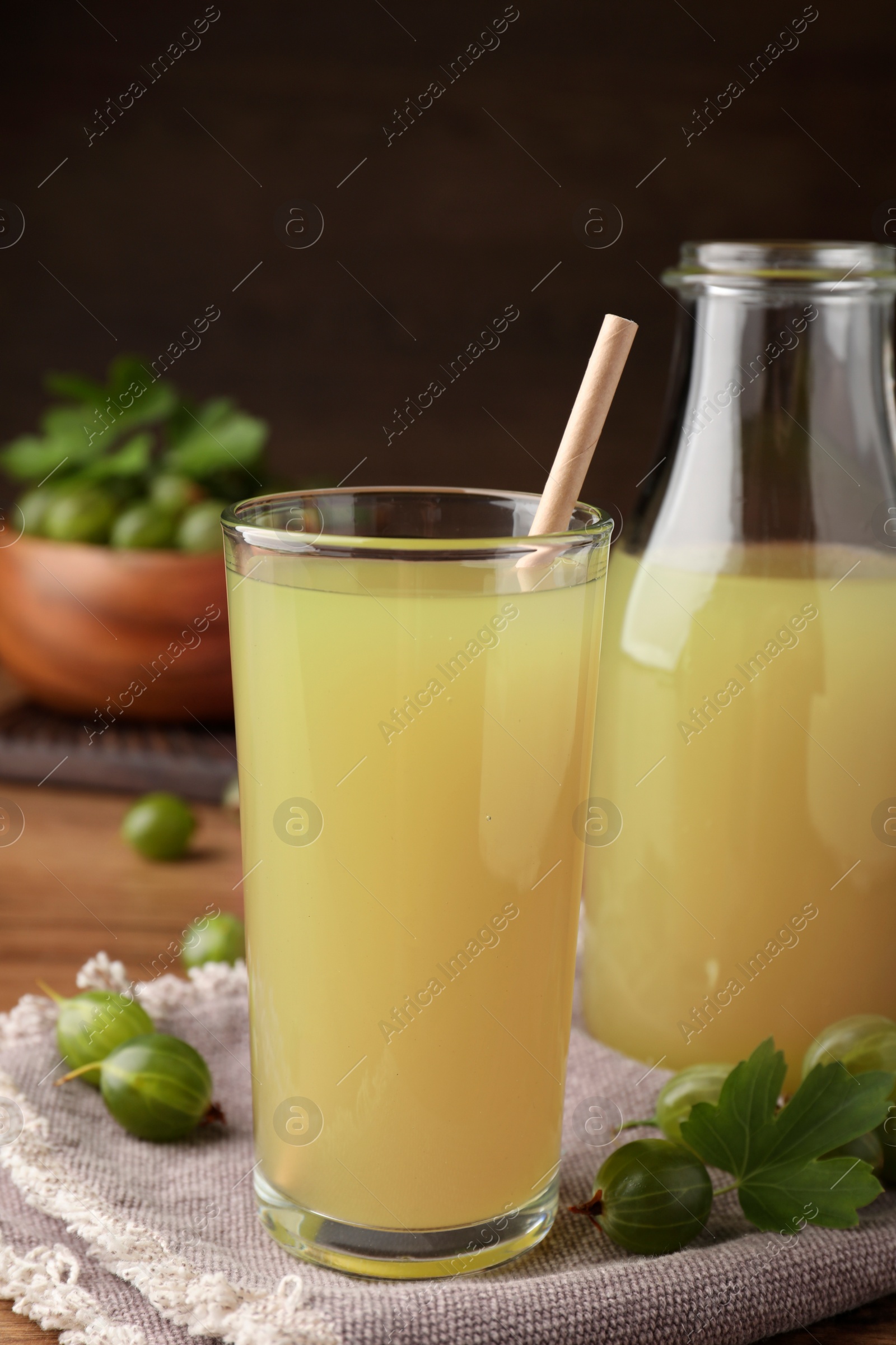 Photo of Tasty gooseberry juice on wooden table, closeup