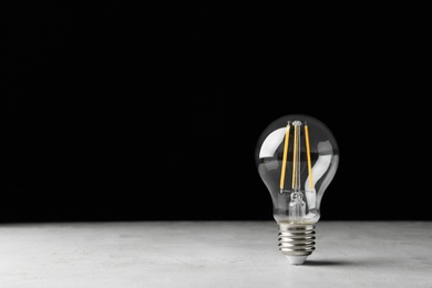 Photo of Vintage lamp bulb on light table against black background. Space for text