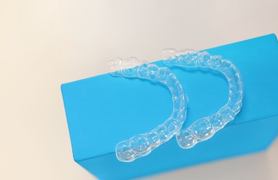 Photo of Transparent dental aligners on beige background, above view. Space for text