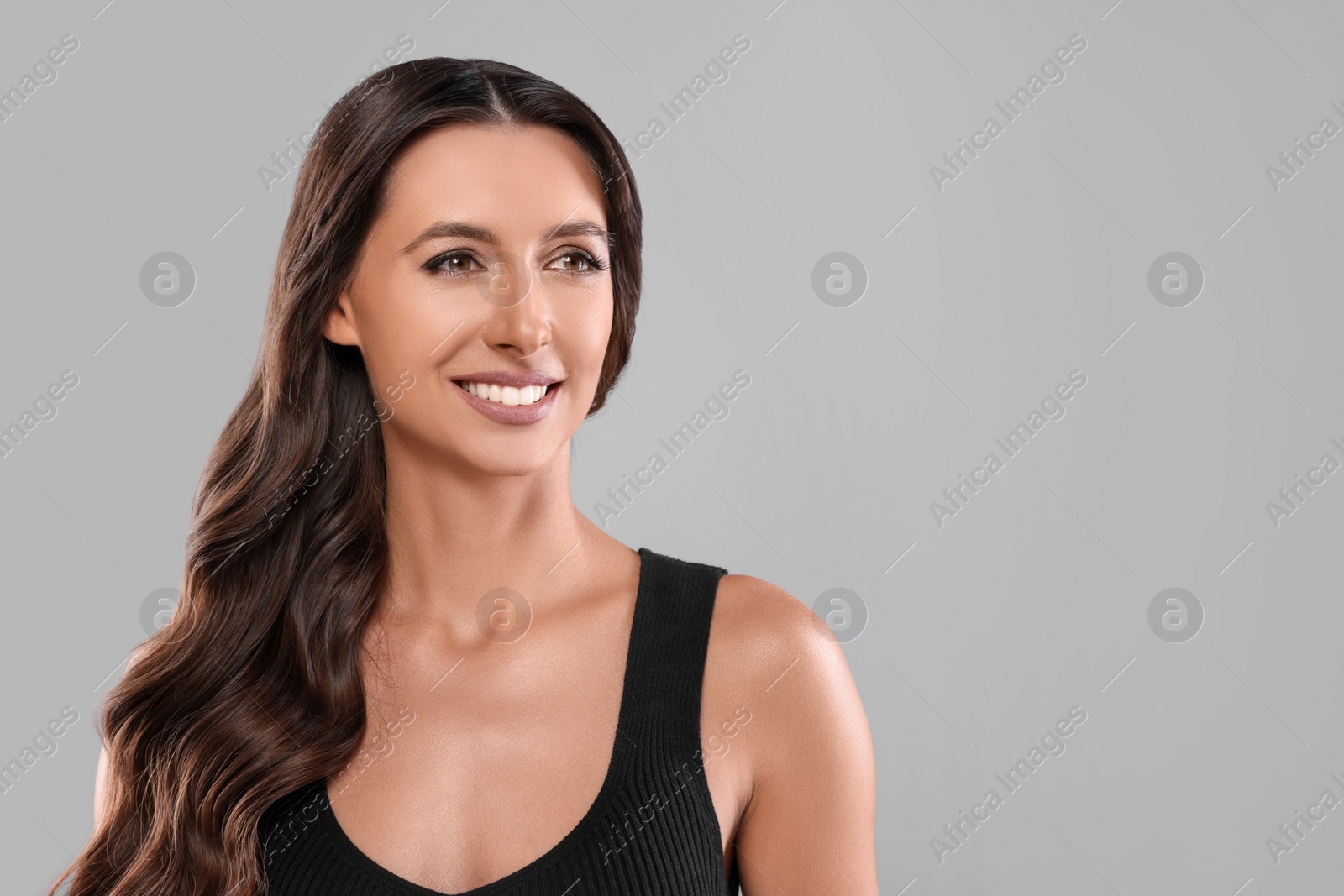 Photo of Hair styling. Beautiful woman with wavy long hair on grey background, space for text