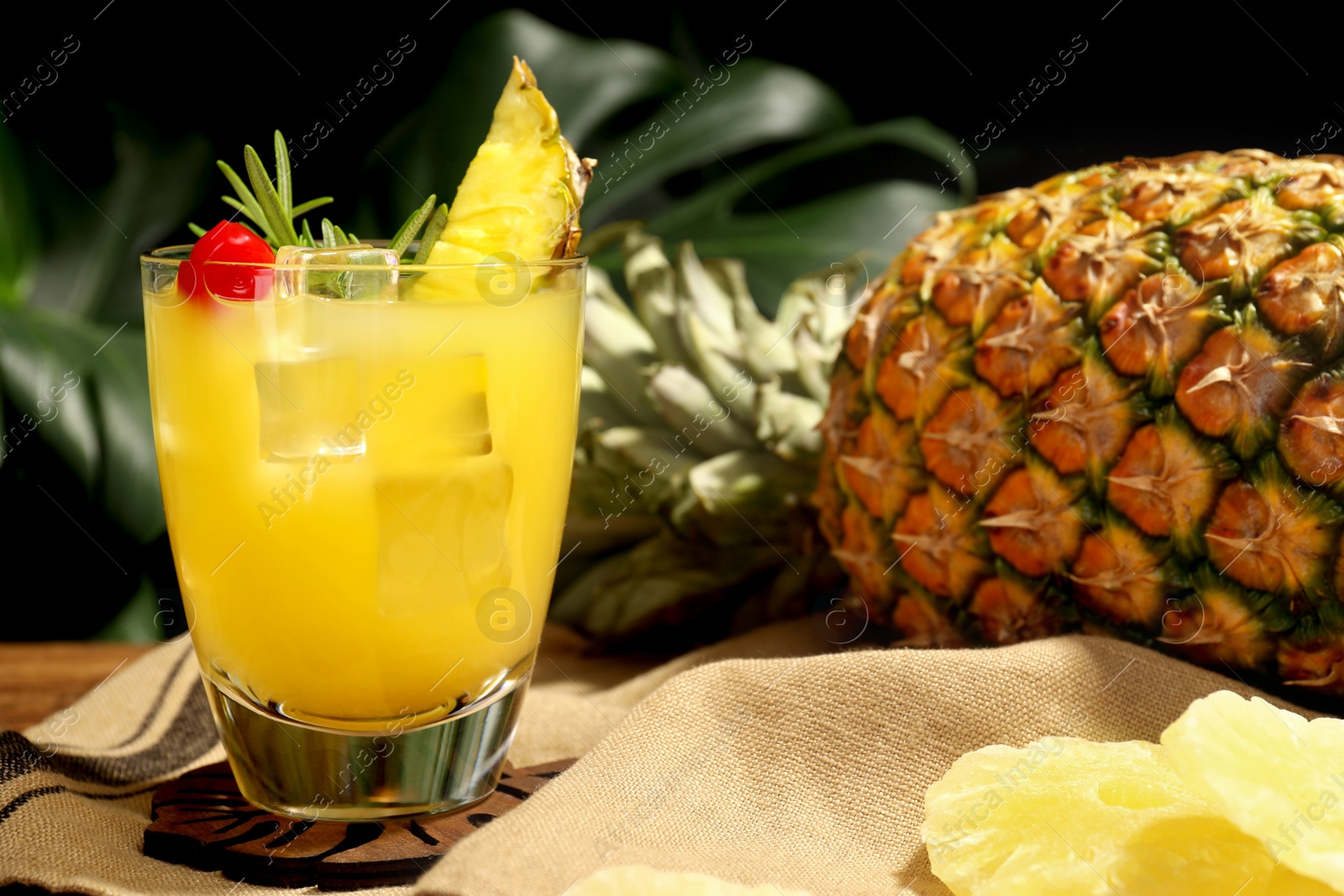Photo of Glass of tasty pineapple cocktail with rosemary and cherry on table, closeup. Space for text