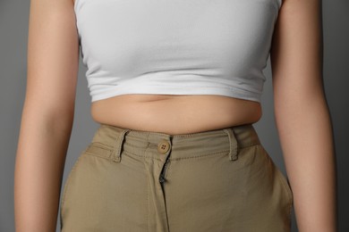 Photo of Overweight woman in tight pants on grey background, closeup