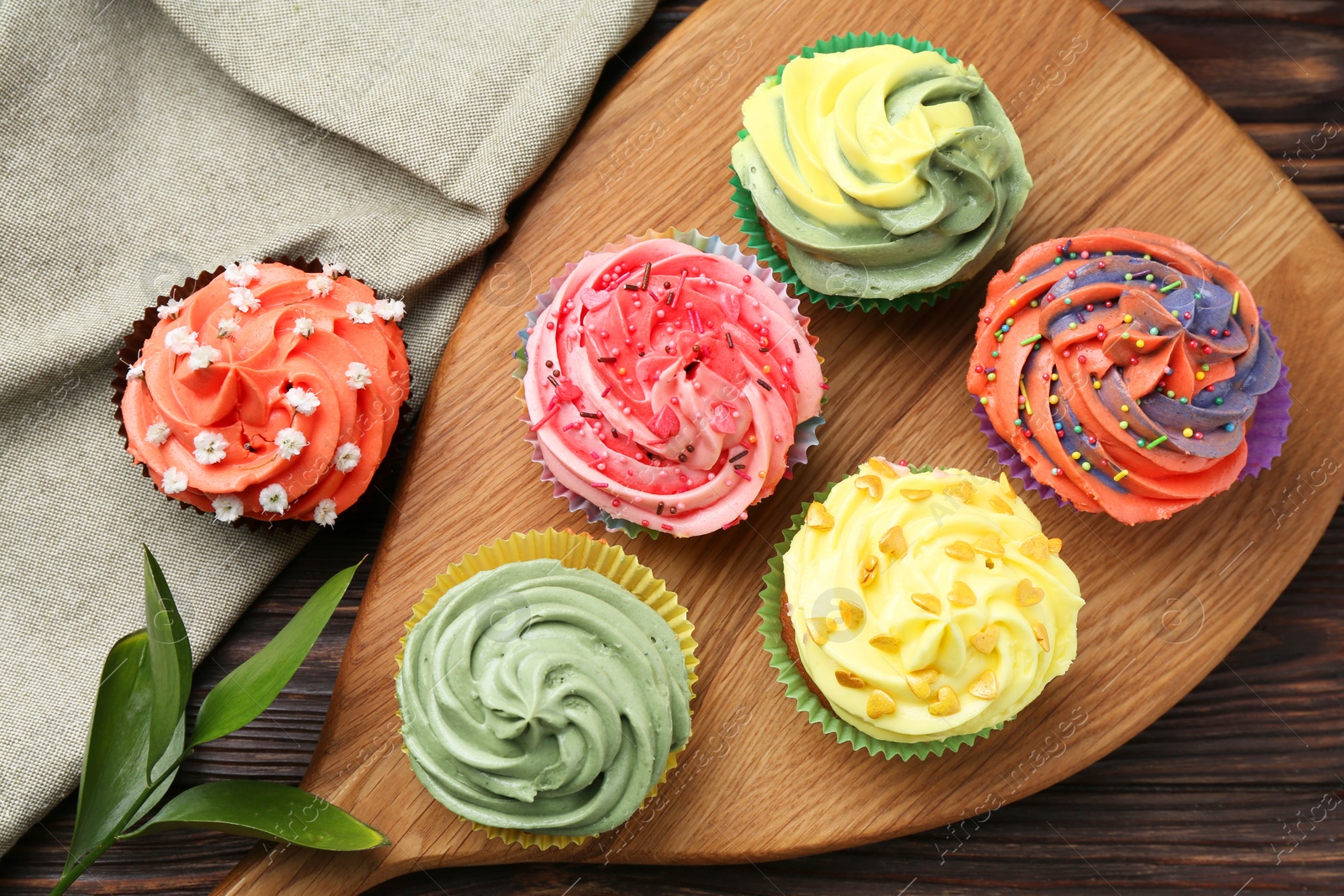 Photo of Delicious cupcake with bright cream on wooden table, flat lay