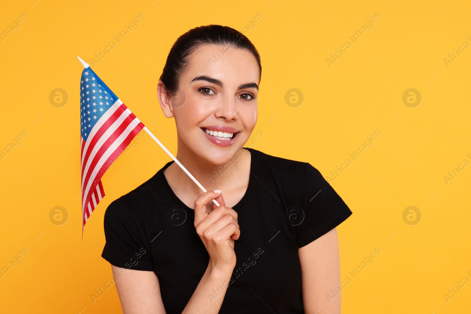 Photo of 4th of July - Independence Day of USA. Happy woman with American flag on yellow background