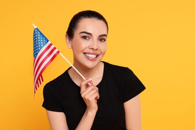 4th of July - Independence Day of USA. Happy woman with American flag on yellow background