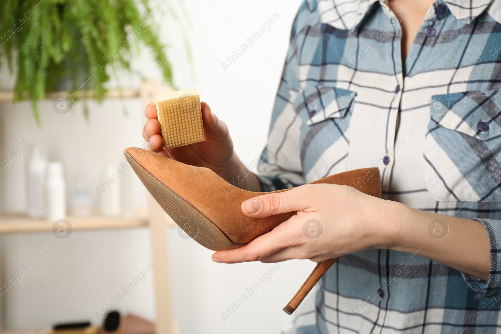 Photo of Woman taking care of stylish shoe indoors, closeup