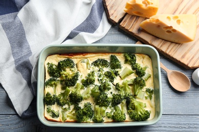 Photo of Tasty broccoli casserole in baking dish on wooden table, flat lay