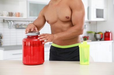 Photo of Young shirtless athletic man preparing protein shake in kitchen, closeup view