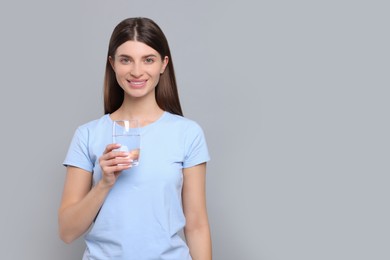 Photo of Healthy habit. Portrait of happy woman holding glass with fresh water on grey background. Space for text