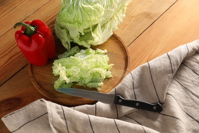 Photo of Fresh Chinese cabbage, pepper and knife on wooden table, above view