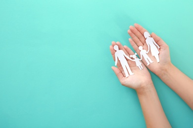 Photo of Woman holding paper family cutout on color background, top view