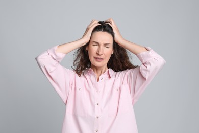 Photo of Mature woman suffering from headache on light grey background