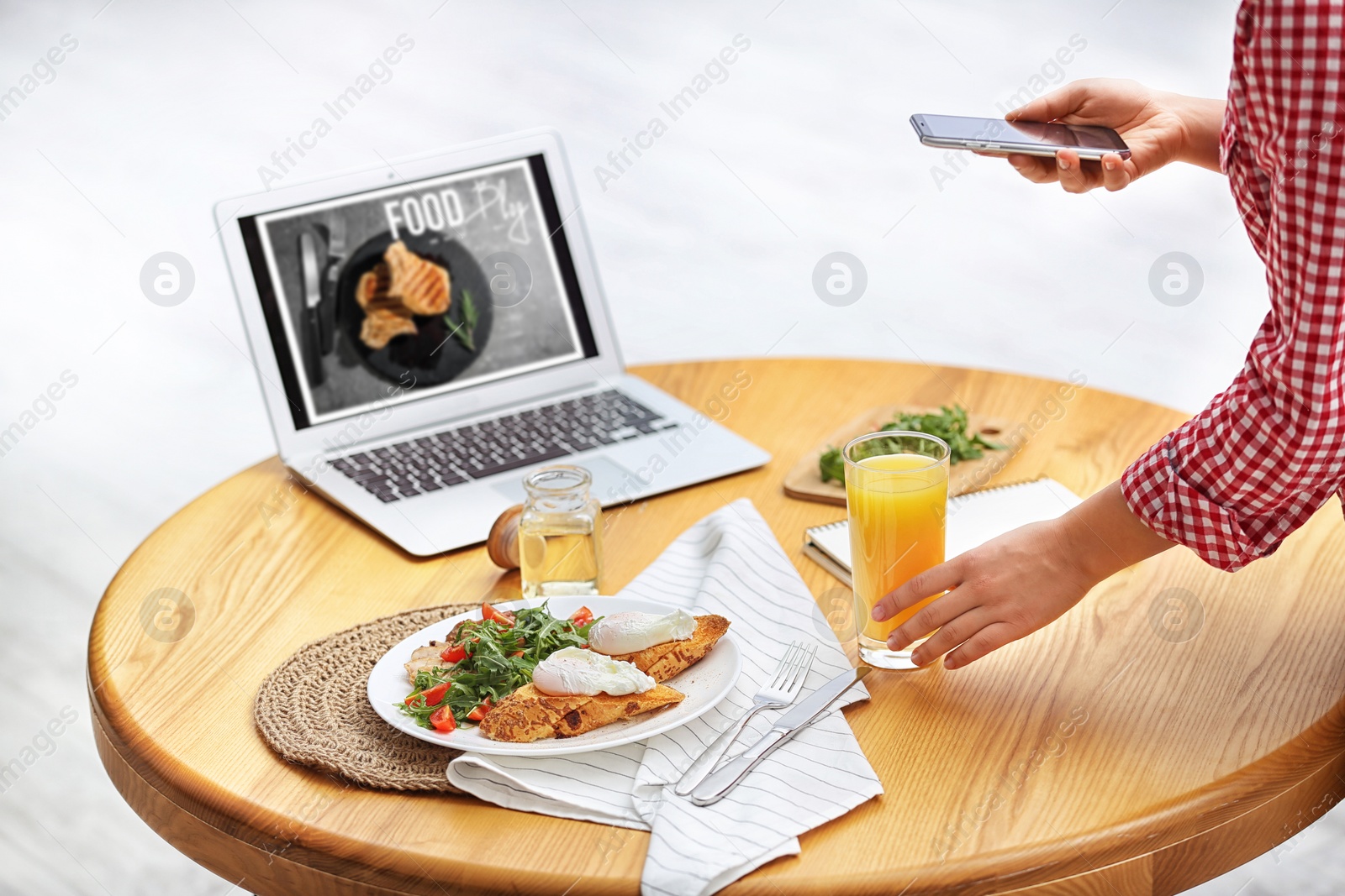 Photo of Food blogger taking photo of her lunch at wooden table indoors, closeup