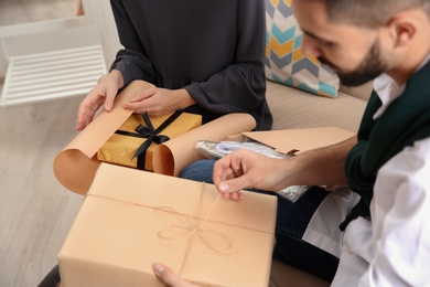 Photo of Young couple opening parcels in living room, closeup