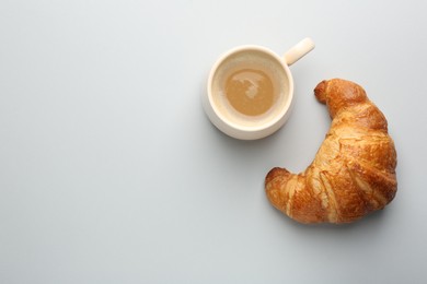 Photo of Delicious fresh croissant and cup of coffee on light background, flat lay. Space for text