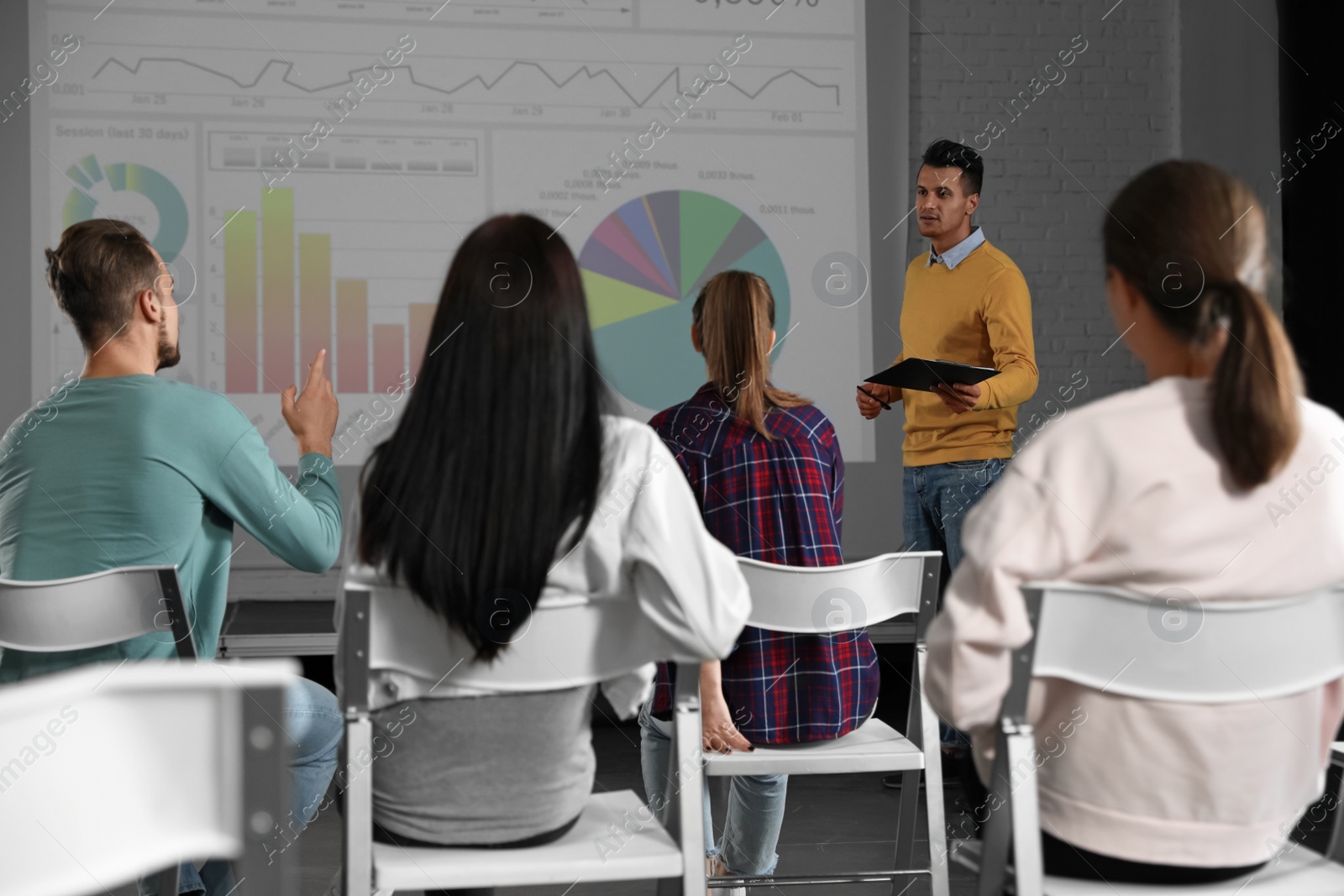 Photo of Male business trainer giving lecture in conference room with projection screen