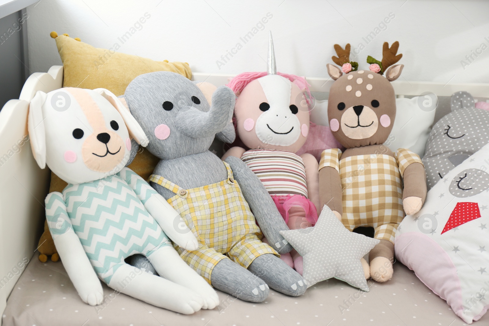 Photo of Cute toys and pillows on bed in baby room. Interior elements