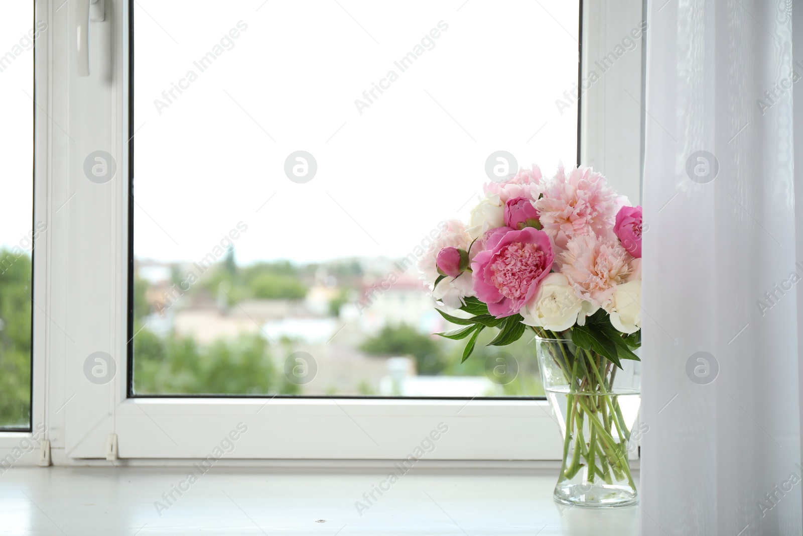 Photo of Beautiful peony bouquet in vase on windowsill indoors. Space for text