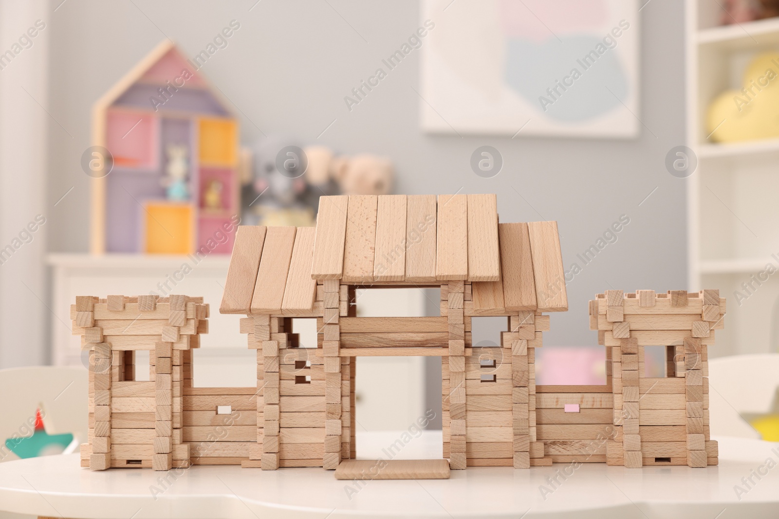 Photo of Wooden entry gate on white table indoors. Children's toy