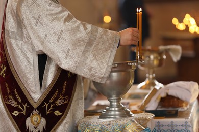 Photo of Priest taking burning candle in church, closeup. Baptism ceremony