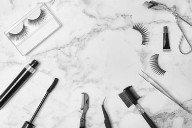 Photo of Flat lay composition with false eyelashes and cosmetic tools on light background