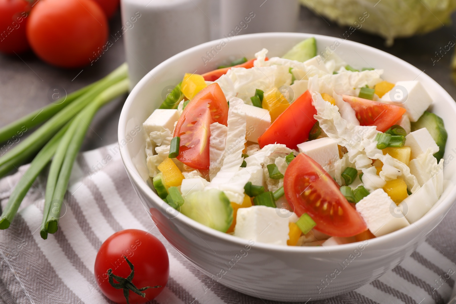 Photo of Tasty salad with Chinese cabbage, cheese, pepper, tomato and green onion on table, closeup